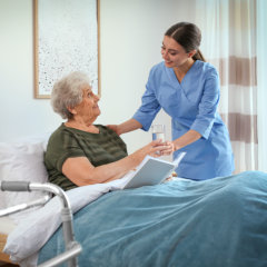 caregiver assist her patient in drinking medicine