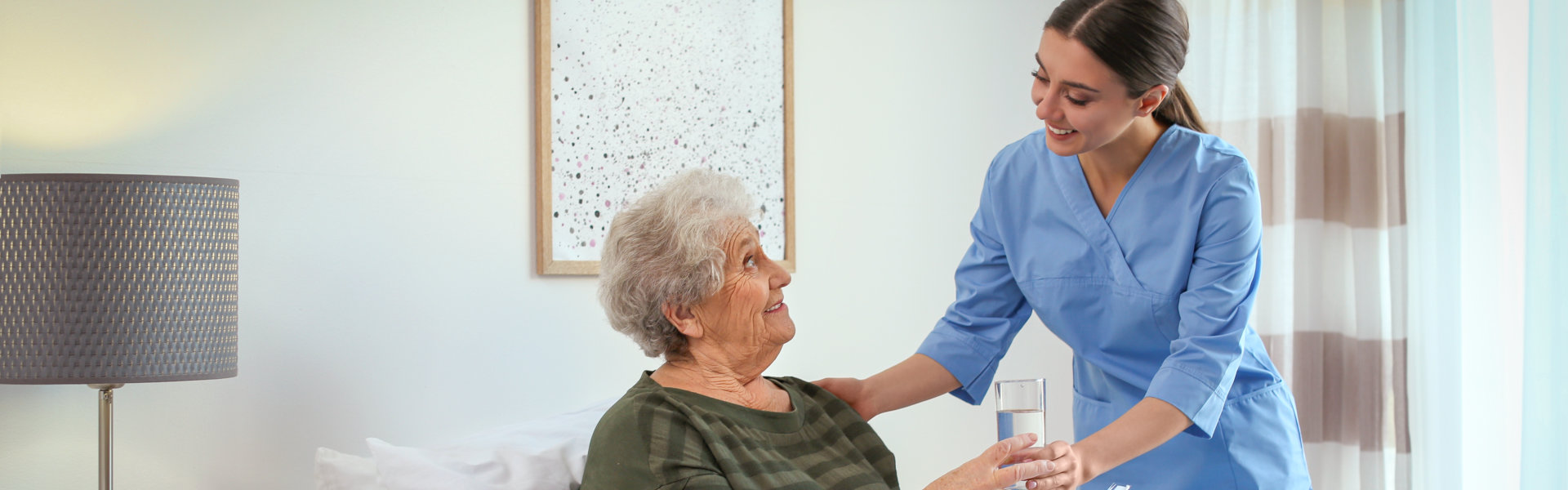 caregiver assist her patient in drinking water